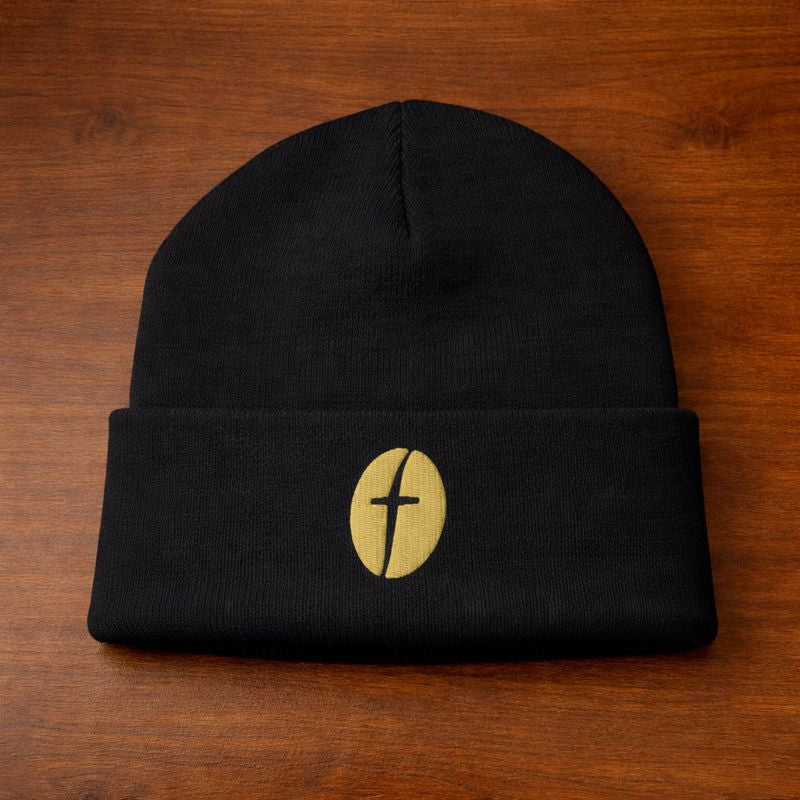Black beanie with a gold emblem on a wooden surface