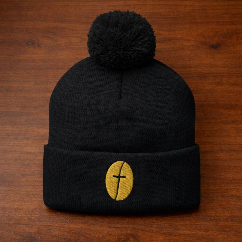 Black beanie with a gold emblem on a wooden surface