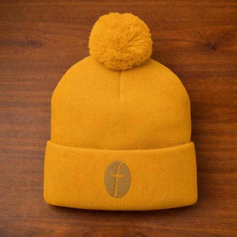 Yellow beanie with pom-pom on a wooden surface